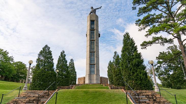 Two sets of stairs leading to a tower with a cast iron statue on top on a nice day