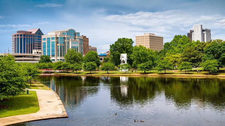 Buildings behind a pond in a park filled with plants and trees