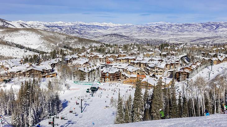 A view over a ski resort with snowy mountains, alpine trees, and lodges