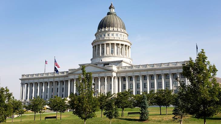 A state capitol building with a domed roof next to grass and trees