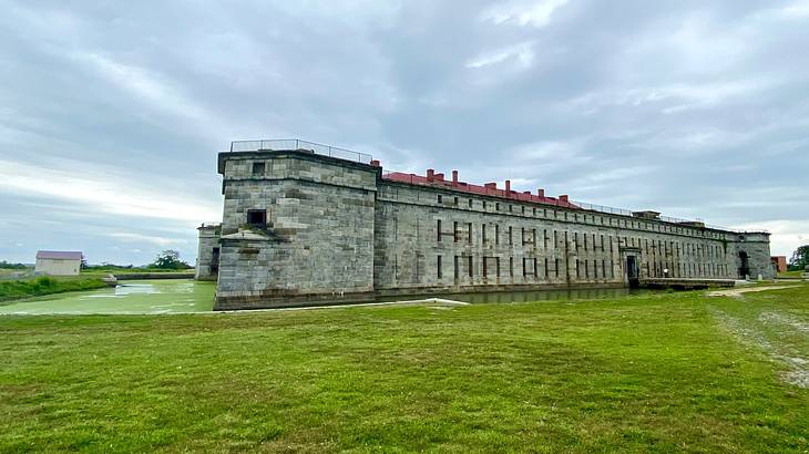 A grey stone fort on grass under a cloudy sky