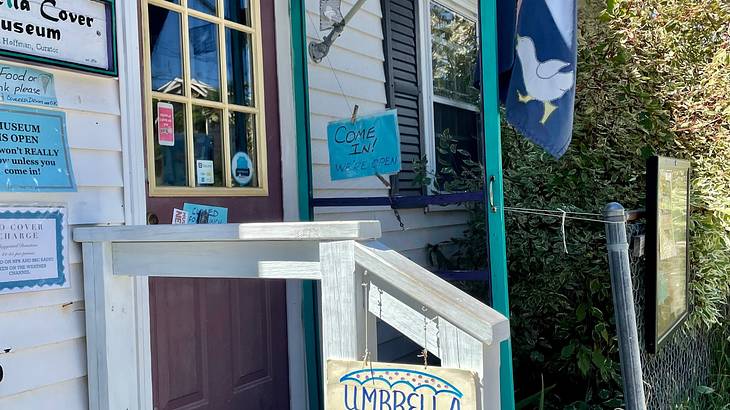 A white building with a flag and signs on the wall and small staircase