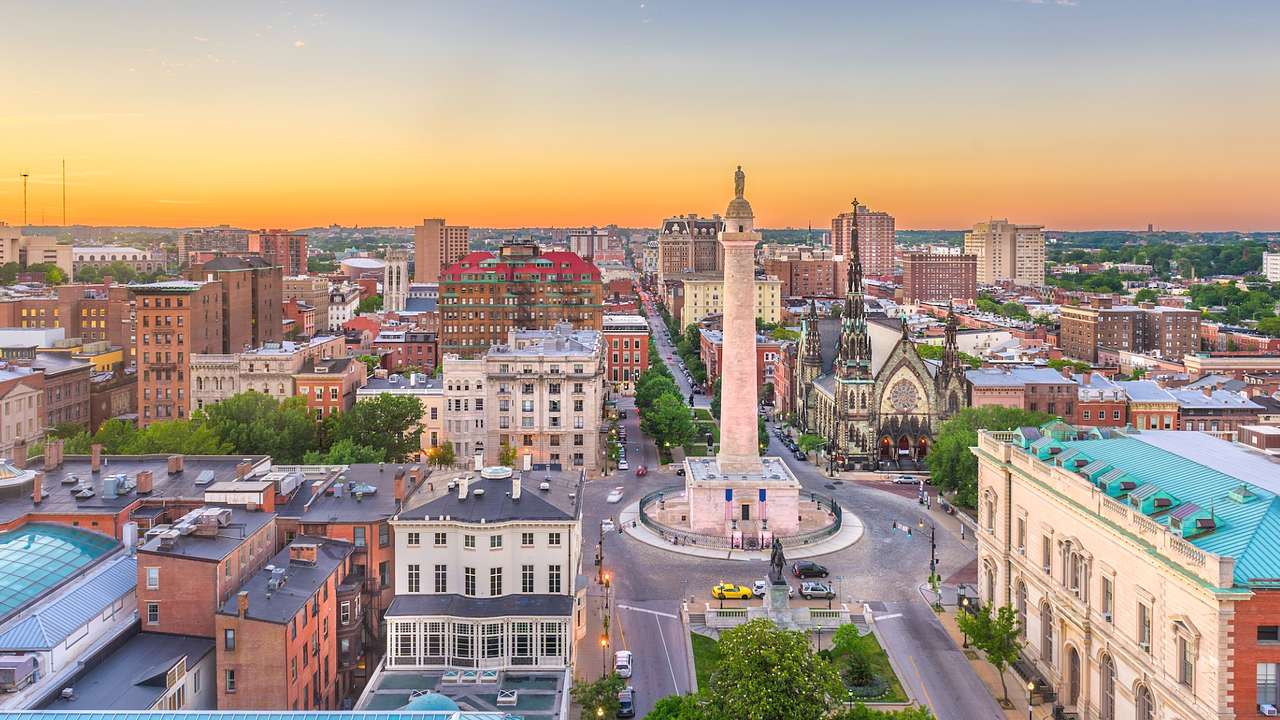 A view over Baltimore at sunset with buildings and a column structure on a roundabout