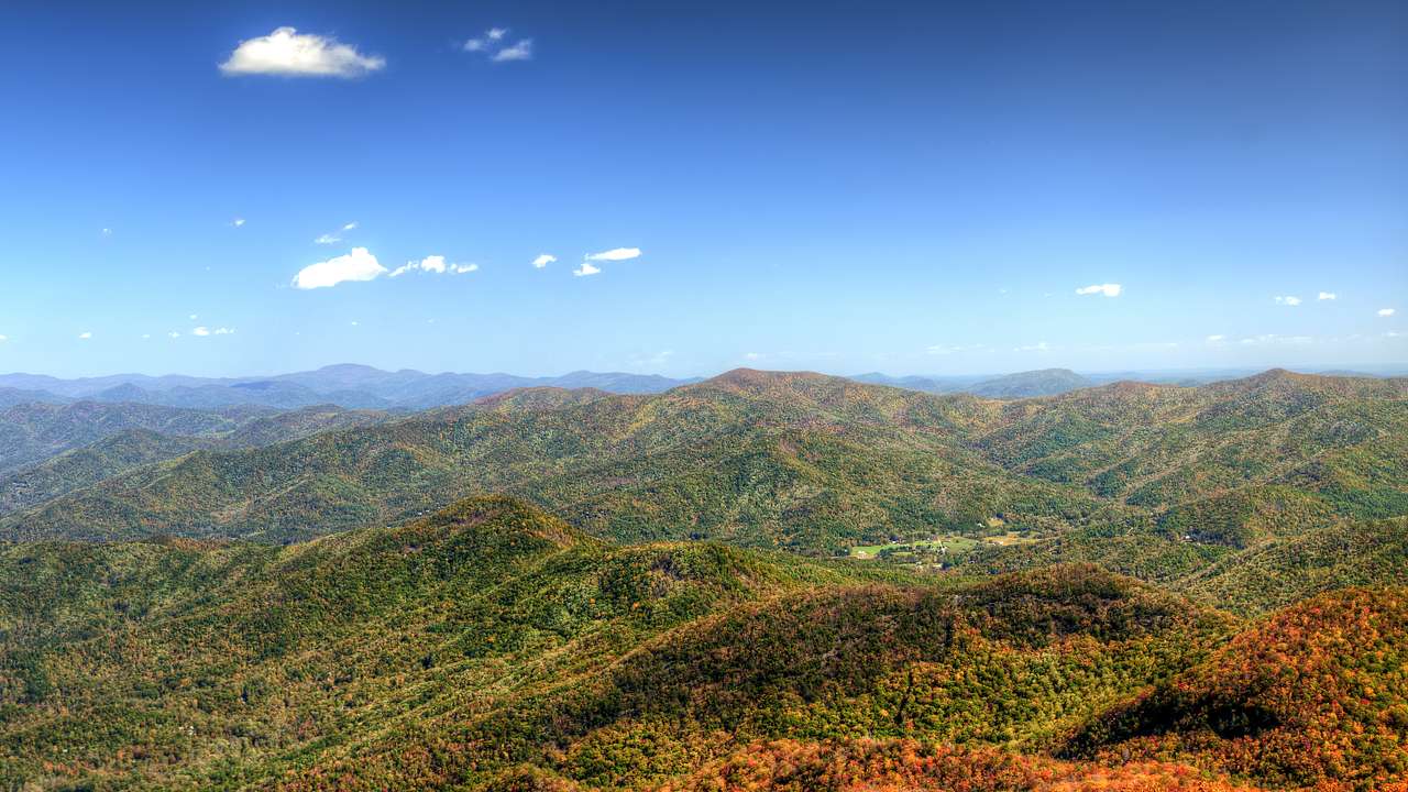 Aerial view of mountains in hues of green and orange on a foggy morning