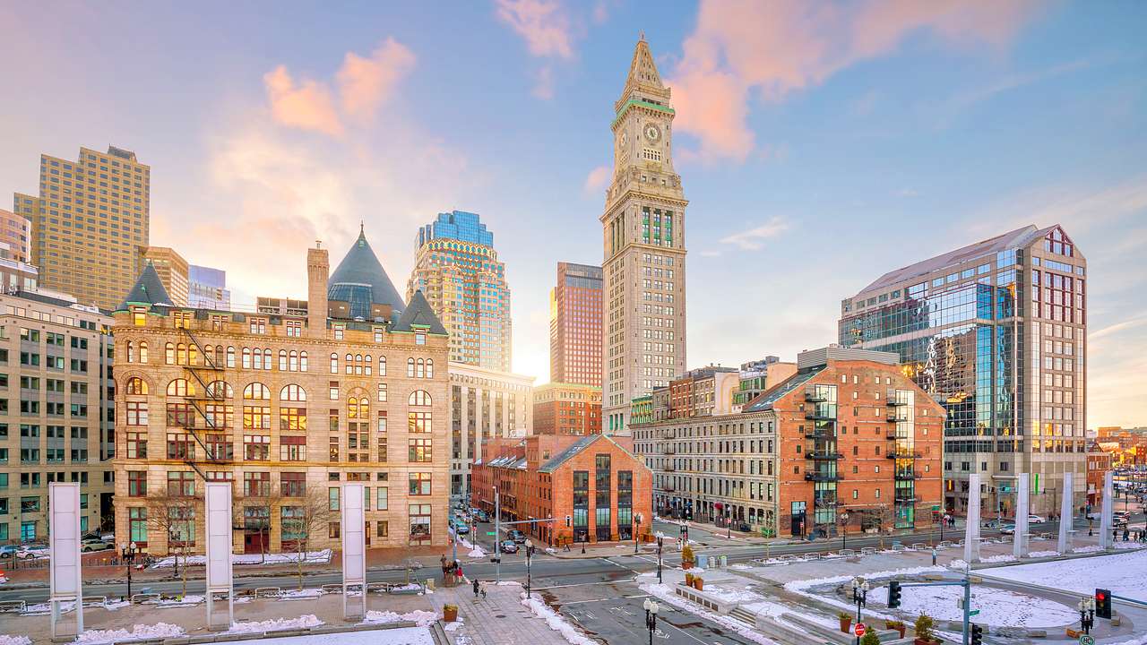 A city with buildings and a clock tower with a dusting of snow on the ground
