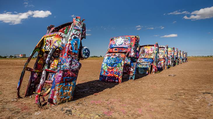 A group of colorful Cadillacs planted nose down in the soil on a nice day