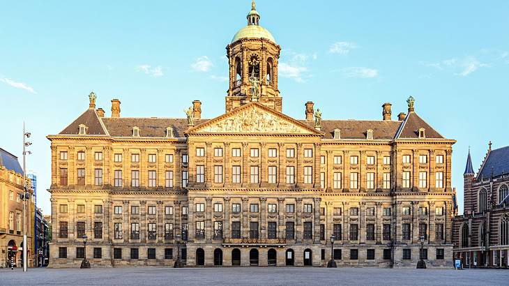 A large palace-style building with a tower and many windows next to a square