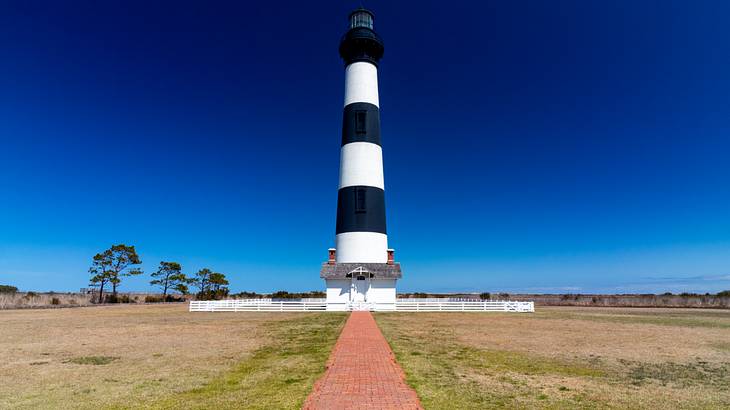 A black and white striped lighthouse against blue sky