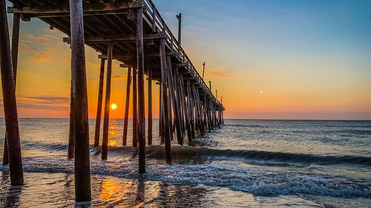 Underneath a large wooden pier with gentle waves Underneath a large wooden pier with gentle waves