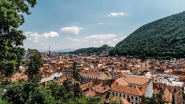 View over building tops surrounded by green hills, Brasov, Romania