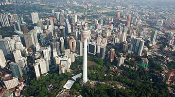 Aerial view of a tall tower in the midst of city buildings and green trees