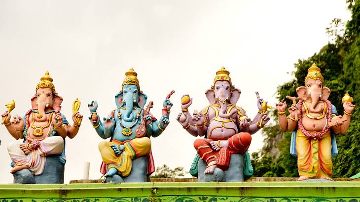 Up close shot of four cross-legged elephant statues on a rooftop