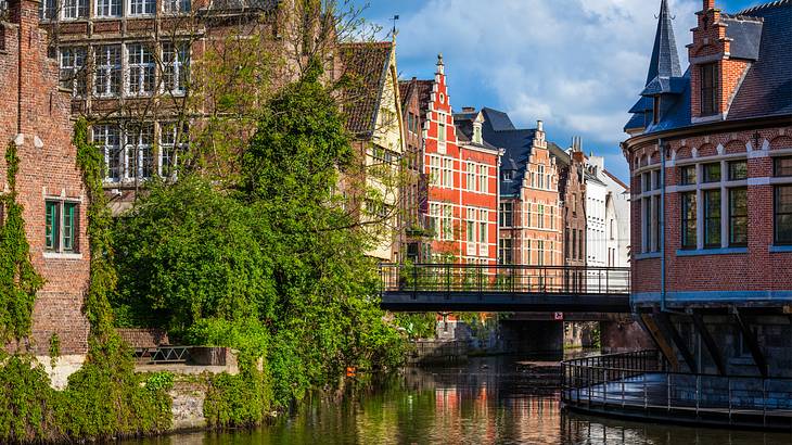 Old town buildings on both sides of a canal, with green trees on the left