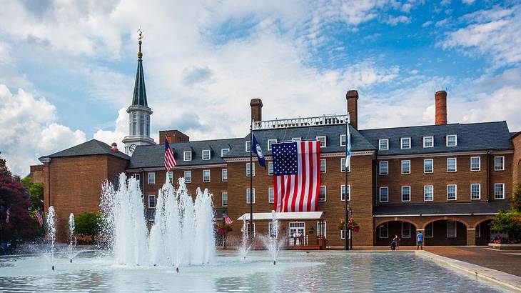 A large brick building with a fountain in front of it and a US flag on the building