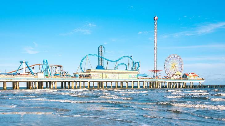 Fair rides on a coastal pier with ocean water surrounding it Fair rides on a coastal pier with ocean water surrounding it