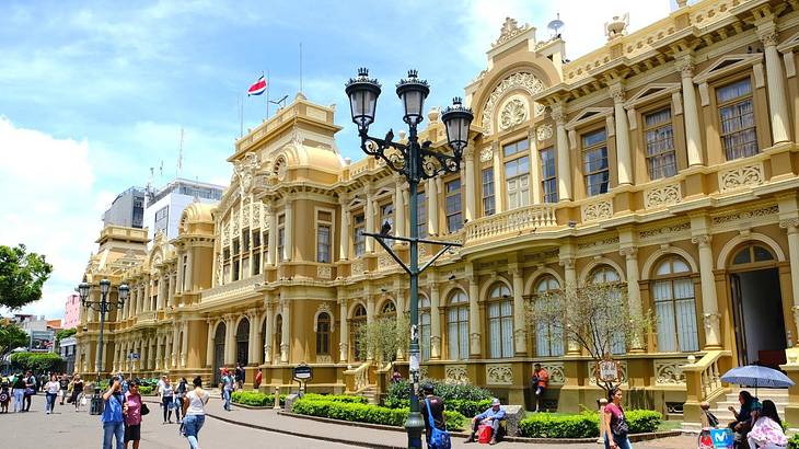 A regal building with a street in front of it that people are walking along