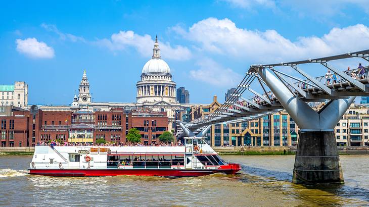 A river with a paddle steamer and a bridge against some buildings and a cathedral