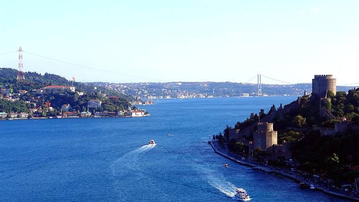 A blue waterway with boats on the water and towns on either side