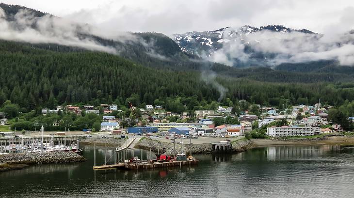 A coastal town at the foot of snowy mountains on a foggy day