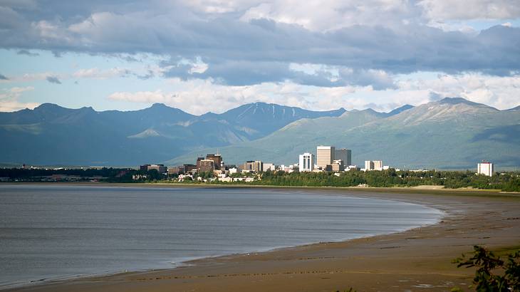 A coastal city with buildings along a beach and mountains in the background