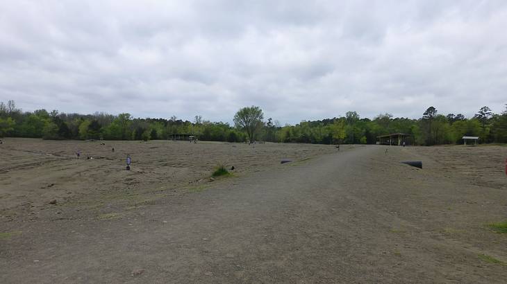 Several markers on a wide barren field with trees behind it
