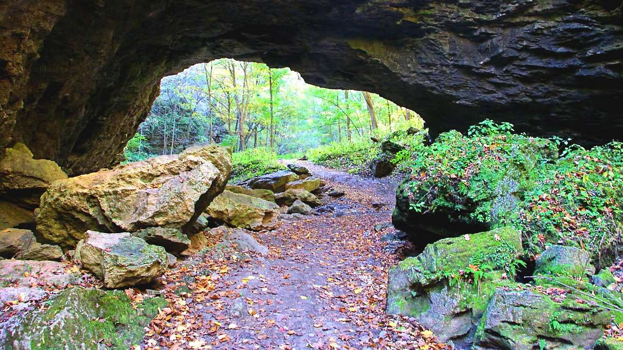 A walkway surrounded by rocks with a natural bridge above