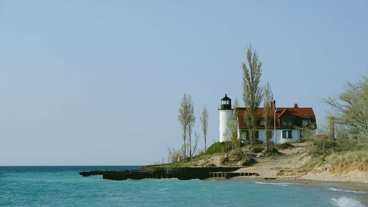 Red, white, and blue lighthouse on a sandy coast on a clear day