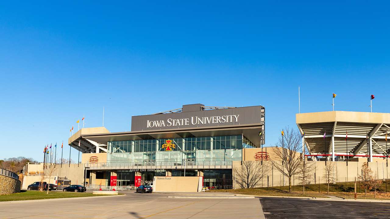 A parking lot outside a stadium building with a signboard of "Iowa State University"