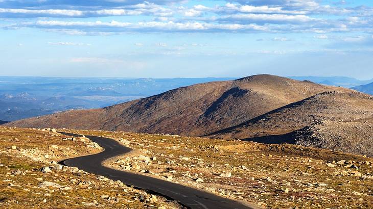 A paved road winding through top of a rugged-mountainous terrain