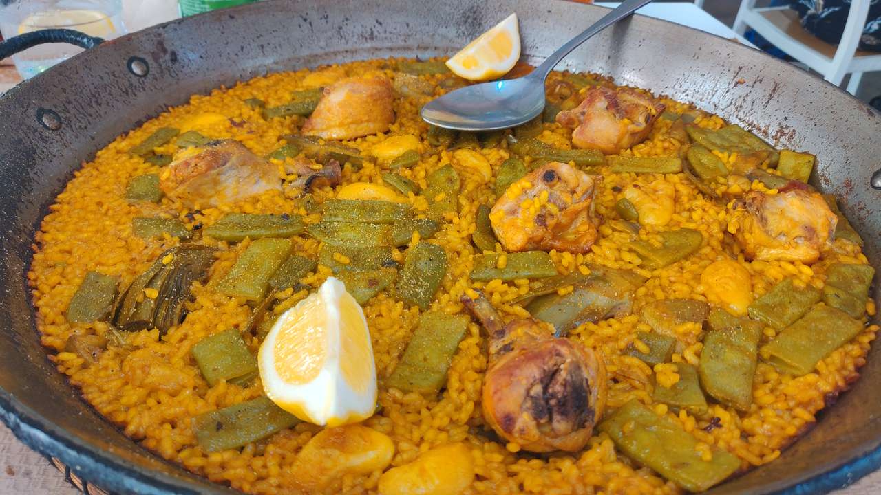 A large dish with orange colored rice and pieces of meat