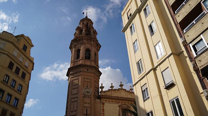 A tall church bell tower in front of blue skies with some clouds