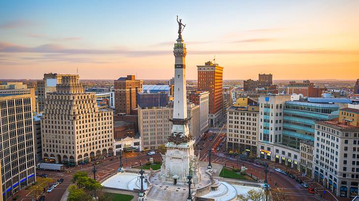 A town square with a statue surrounded by tall buildings under a sunset sky A town square with a statue surrounded by tall buildings under a sunset sky