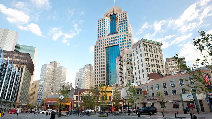 An urban square with tall buildings surrounding it under a blue sky