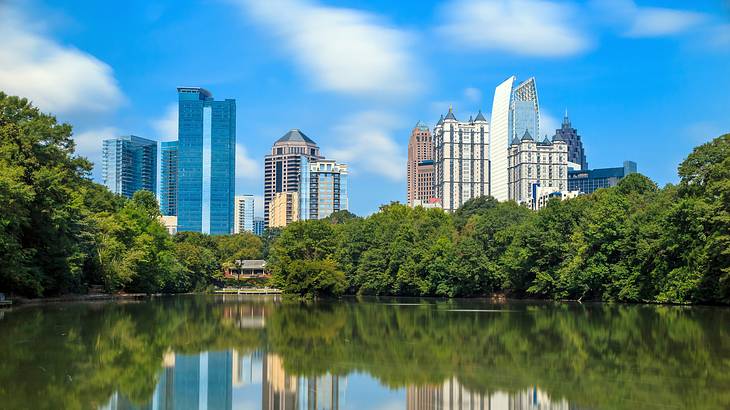 A lake with a reflection in the water of the trees surrounding and a skyline it A lake with a reflection in the water of the trees surrounding and a skyline it