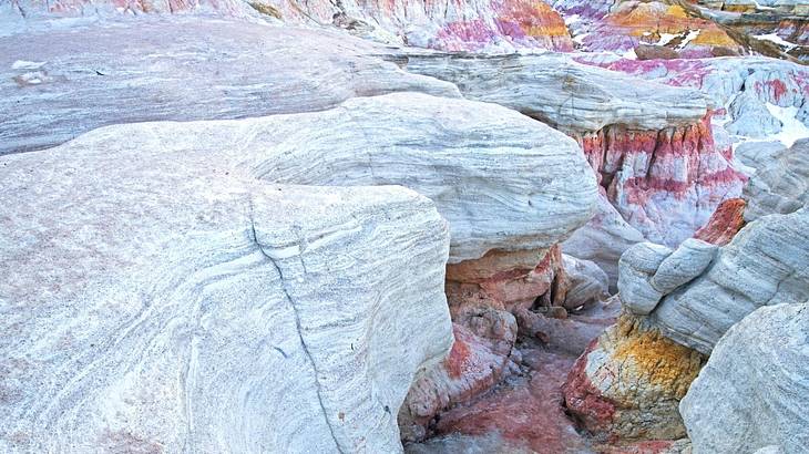 Grey cliffs with pink, yellow, and orange rock interspersed