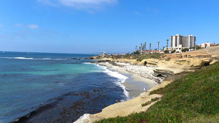 View of a beach with ocean water, sandy shores, and buildings in the distance