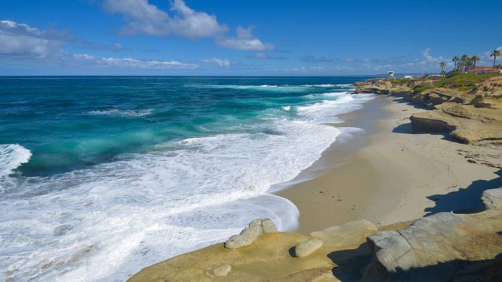 Blue ocean water with white waves crashing onto the sandy shore