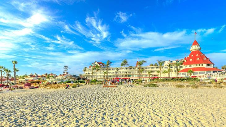 A sandy beach with a white and red hotel in the background