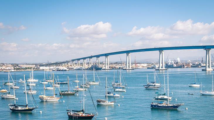 Boats on the water with a bridge in the background under a blue sky