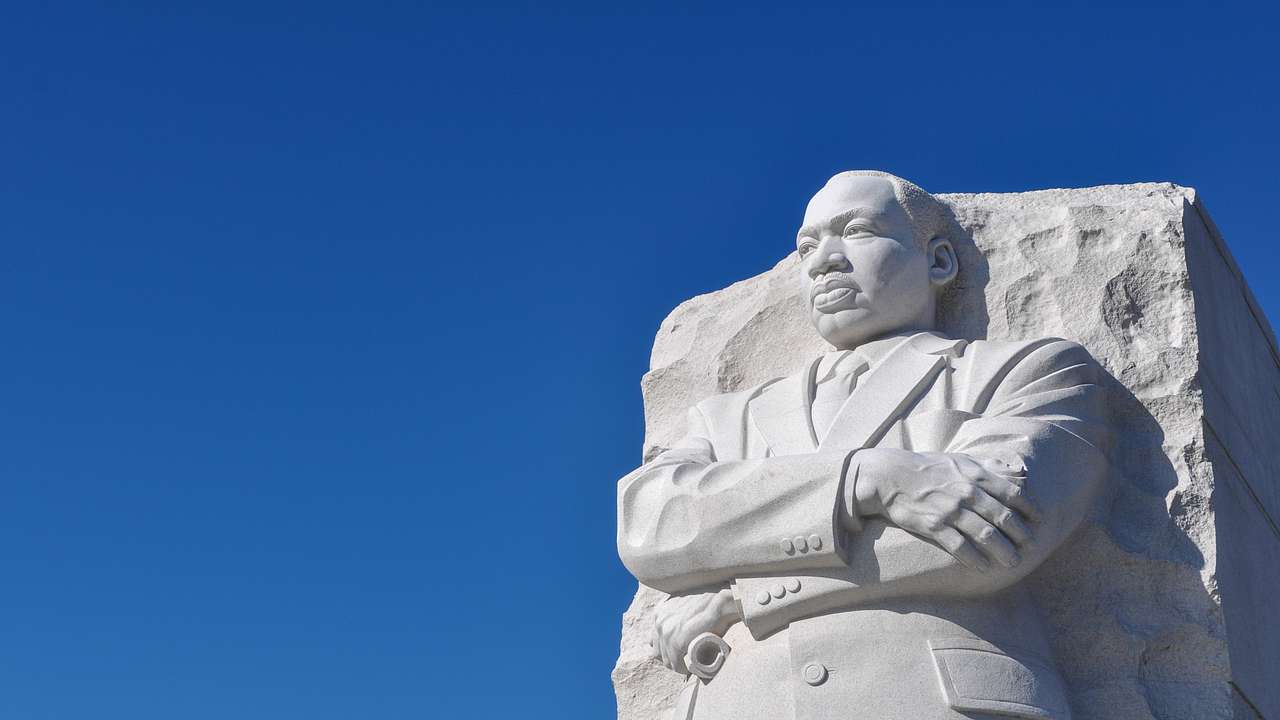 A stone statue of Martin Luther King Jr. with a blue sky behind it