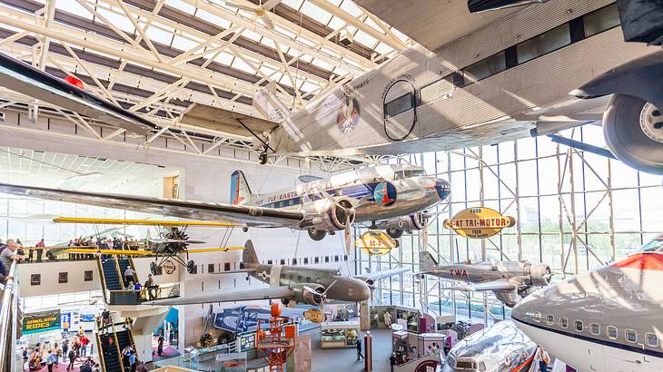 Airplanes on display in a museum with a large glass window on one wall