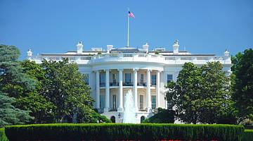 The US White House with a US flag on the roof and trees surrounding it