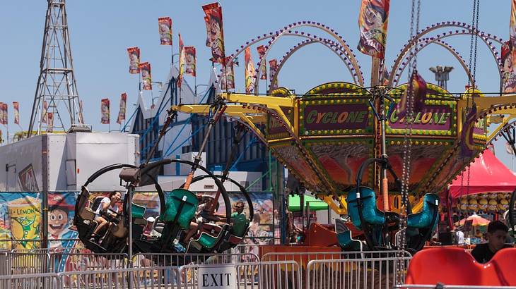 Looking towards a colorful tornado ride swinging under a blue sky at a fair