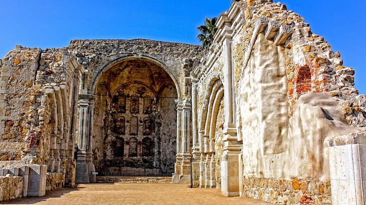 Looking at stone ruins with arches in the middle, against a clear blue sky