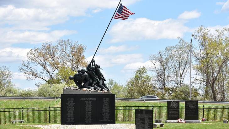 A memorial statue of soldiers lifting an American flag with a park surrounding