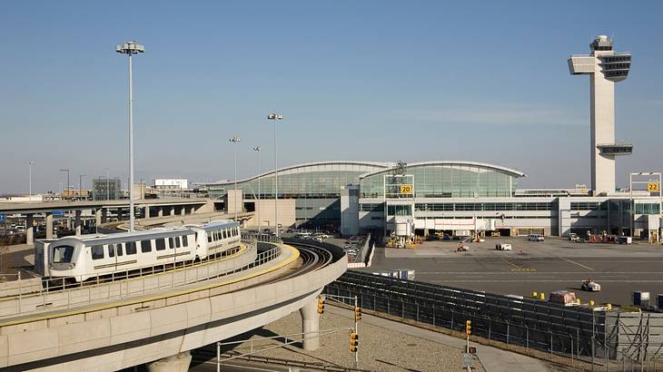 An international airport terminal, a white train and a tall control tower An international airport terminal, a white train and a tall control tower