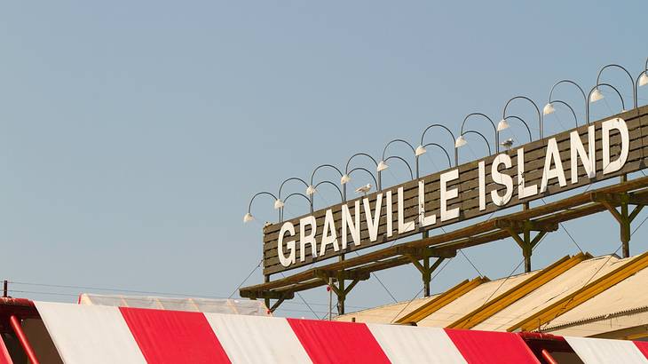 Half of the Granville Island Public Market sign above a red and white building top Half of the Granville Island Public Market sign above a red and white building top
