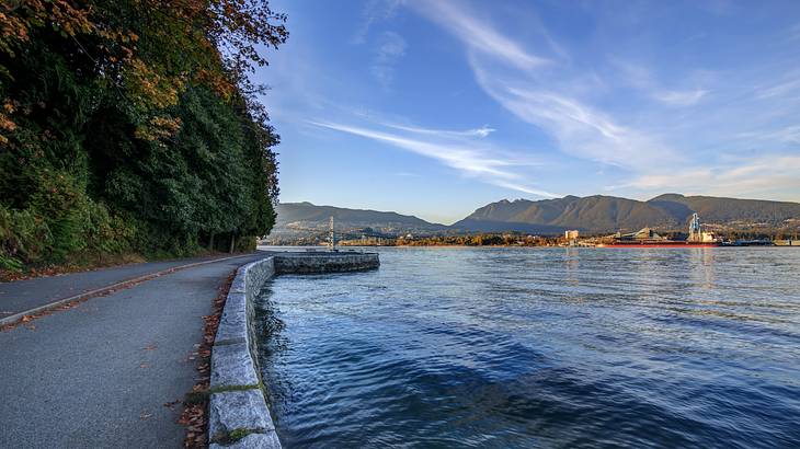 Bicycle and pedestrian walkway along water with mountains in the back