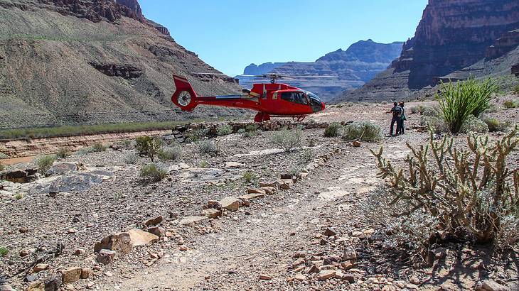 A helicopter landed in a canyon with mountains surrounding it
