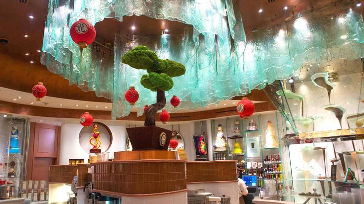 A cafe with a plant, lanterns, and a modern glass chocolate fountain